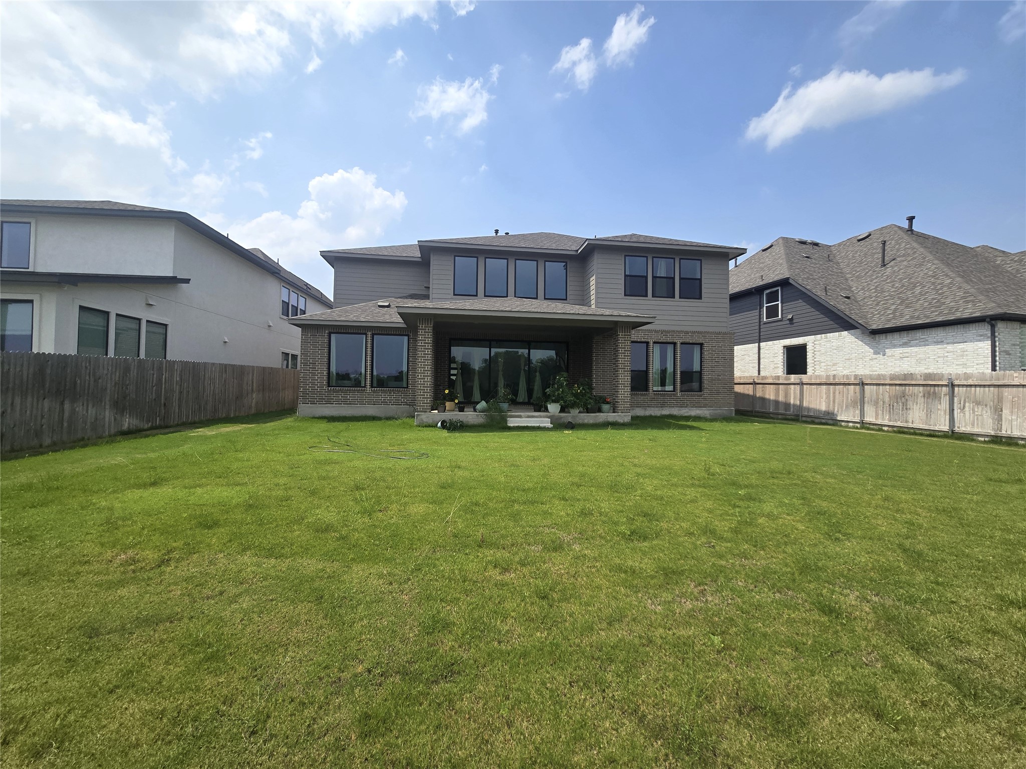 124 Ribera Drive Liberty Hill, TX 78642 - Photo 31 of 40 A spacious grassy yard extends behind a modern home with ample windows and covered patio.