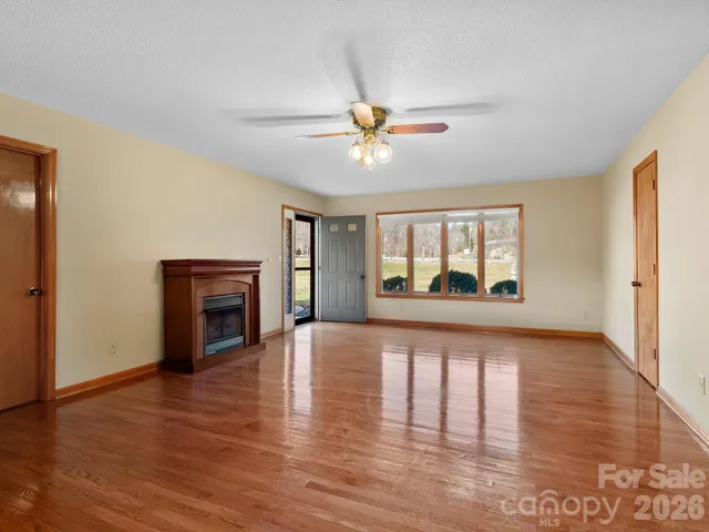 a view of a livingroom with wooden floor a ceiling fan and a window