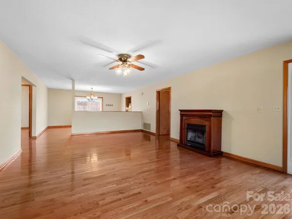 a view of an empty room with a fireplace and wooden floor