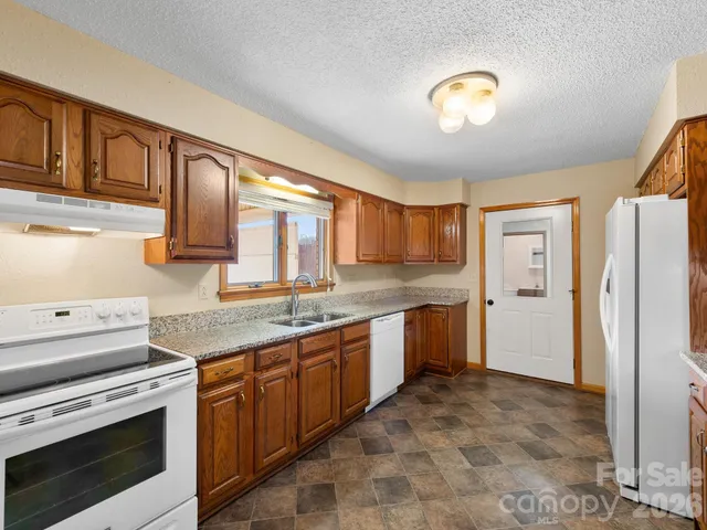 a kitchen with granite countertop a sink cabinets and stainless steel appliances