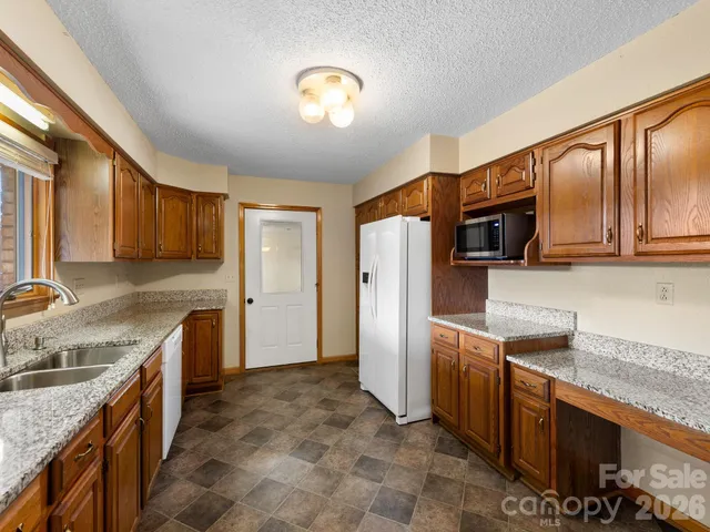 a kitchen with stainless steel appliances granite countertop a refrigerator a stove top oven a sink and dishwasher