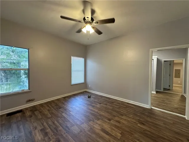 an empty room with wooden floor fan and windows