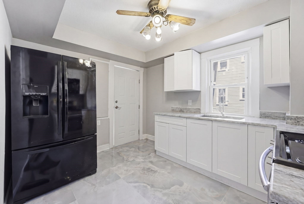 62 Kenyon Street Springfield, MA 01109 - Photo 11 of 26 a kitchen with granite countertop a refrigerator a sink a stove and cabinets
