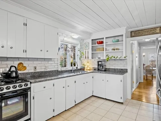 a kitchen with granite countertop white cabinets and stainless steel appliances