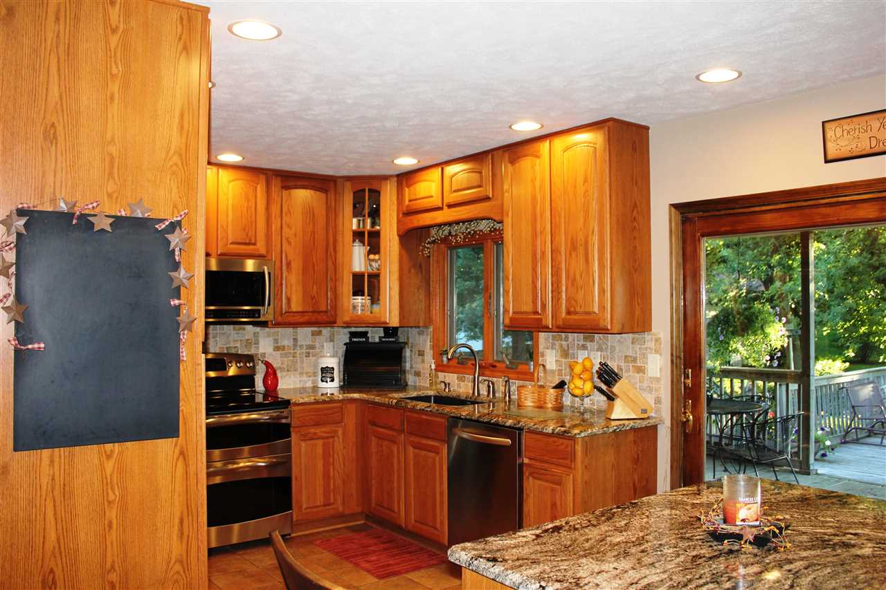 6056 North Knoll Road Monroe Center, IL 61052 - Photo 2 of 24 a kitchen with stainless steel appliances kitchen island granite countertop a refrigerator cabinets and a stove