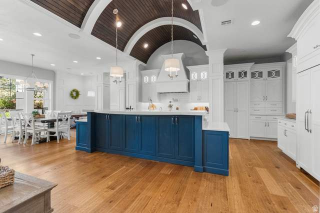 2917 Old Farm Road Washington, UT 84780 - Photo 19 of 105 Two tone kitchen with dual tone cabinetry, a barrel ceiling, hanging light fixtures, glass insert cabinets, and light wood-style floors