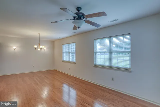 a view of an empty room with a chandelier and wooden floor