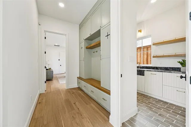 a hallway with white cabinets and wooden floor
