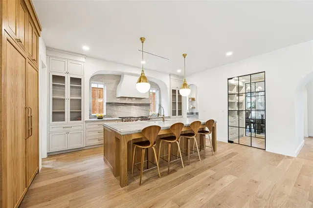 a kitchen with stainless steel appliances granite countertop a stove top oven a sink dishwasher a dining table and chairs with wooden floor