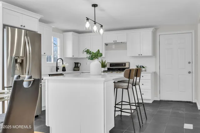 a kitchen with stainless steel appliances granite countertop a refrigerator a sink dishwasher a stove and white cabinets with wooden floor