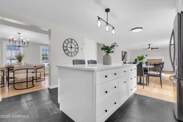 a kitchen with stainless steel appliances kitchen island granite countertop a table chairs sink and cabinets