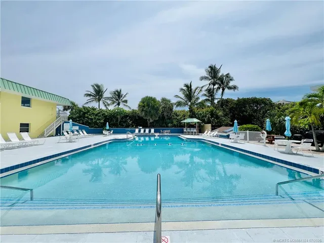a view of patio with table and chairs under an umbrella with a barbeque