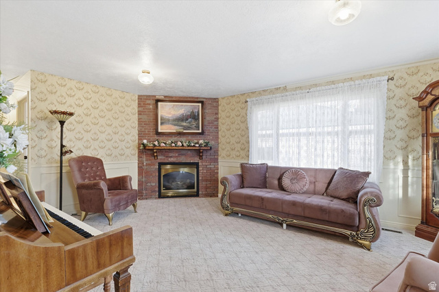 165 Main Street Georgetown, ID 83239 - Photo 5 of 50 Living room with wallpapered walls, a brick fireplace, a wainscoted wall, and carpet