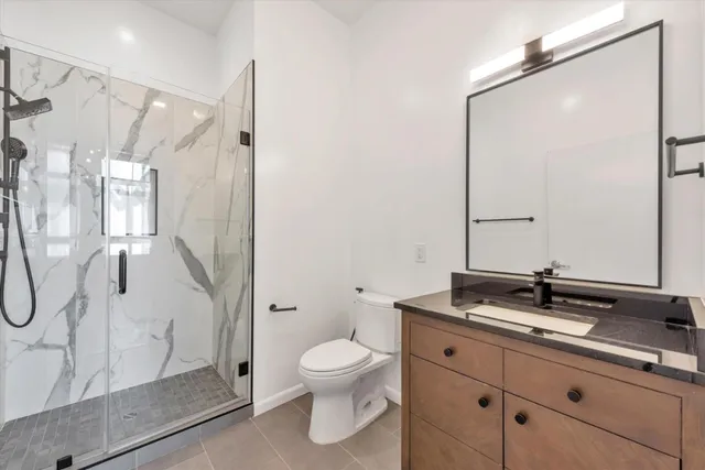 a bathroom with a granite countertop sink a toilet and a mirror