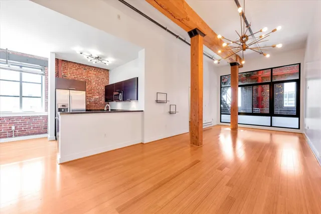 a view of a kitchen with an empty room and wooden floor