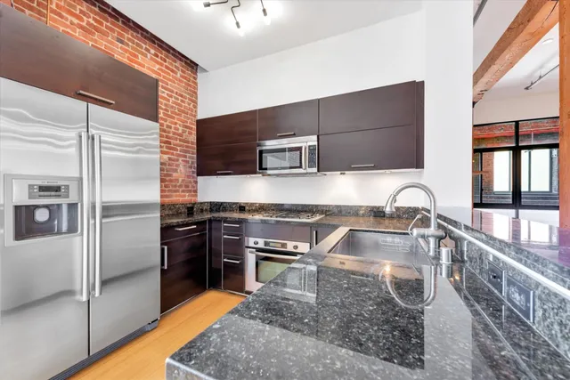 a kitchen with granite countertop a sink stainless steel appliances and cabinets