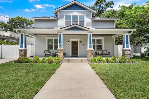 a front view of a house with a yard and potted plants