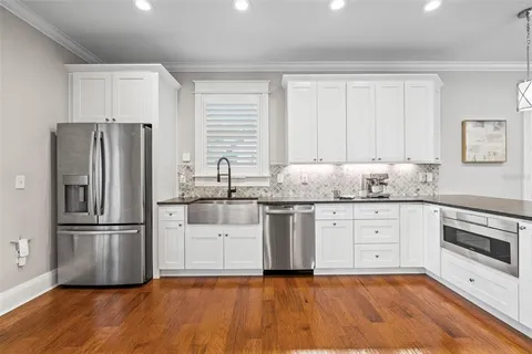 a large kitchen with cabinets wooden floor and stainless steel appliances