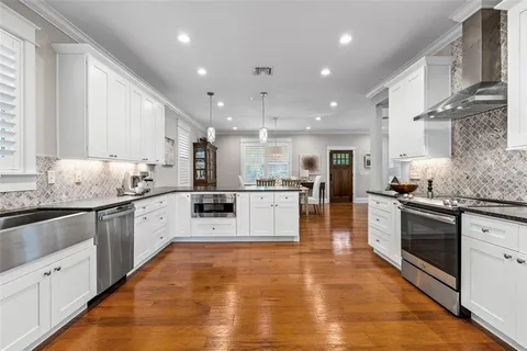 a large white kitchen with stainless steel appliances granite countertop a stove and a sink