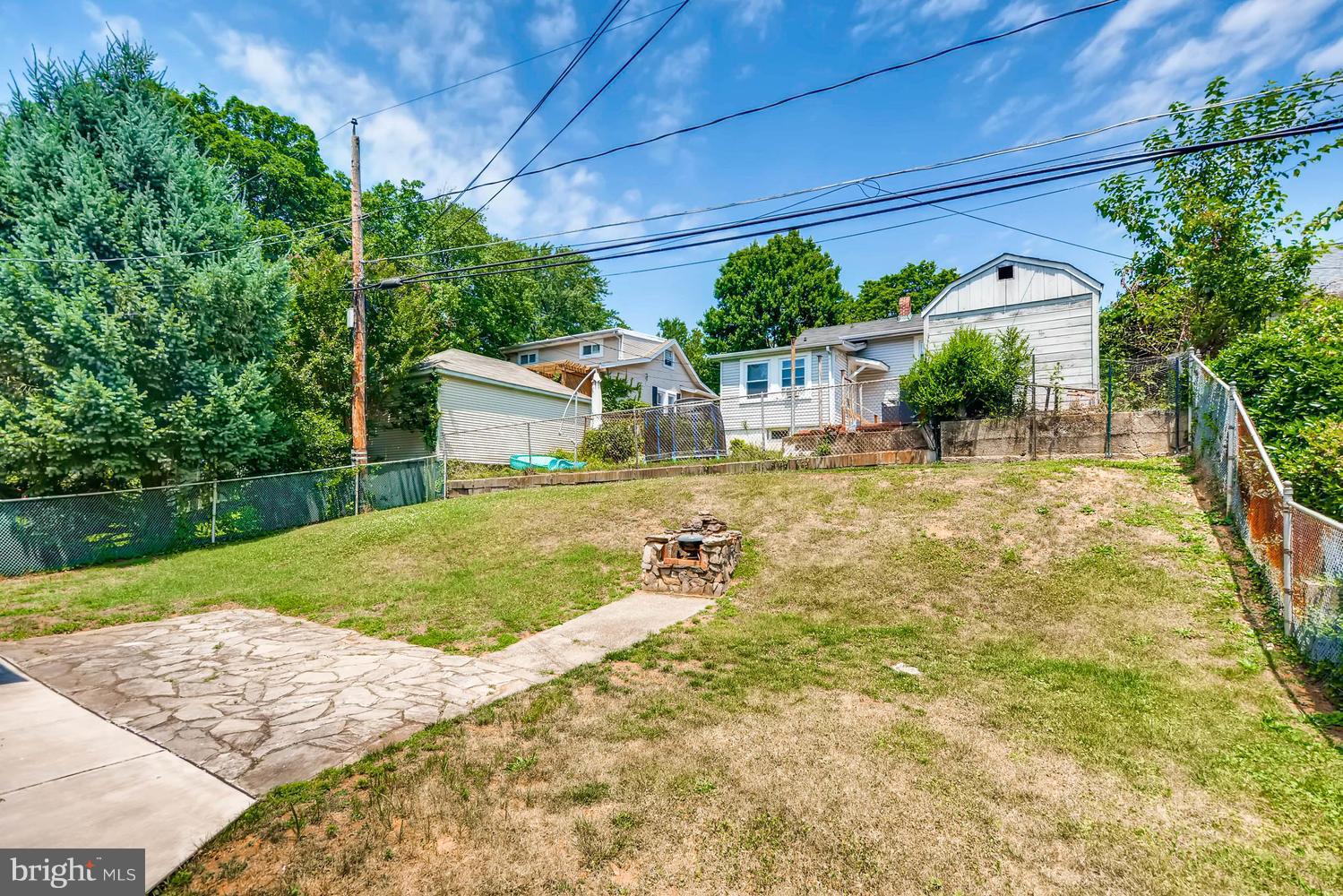 1018 St Albans Road Baltimore, MD 21239 - Photo 27 of 28 a backyard of a house with plants and large trees with lawn chairs