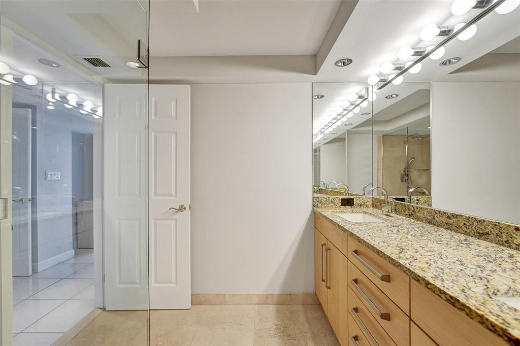 936 Intracoastal Drive, Unit 12C Fort Lauderdale, FL 33304 - Photo 33 of 65 a bathroom with a granite countertop sink a mirror and a shower