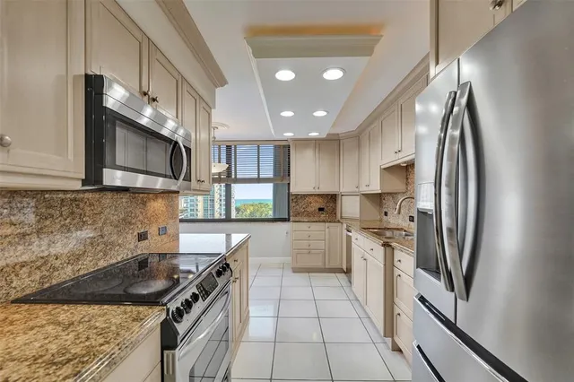 a kitchen that has a lot of white cabinets and stainless steel appliances