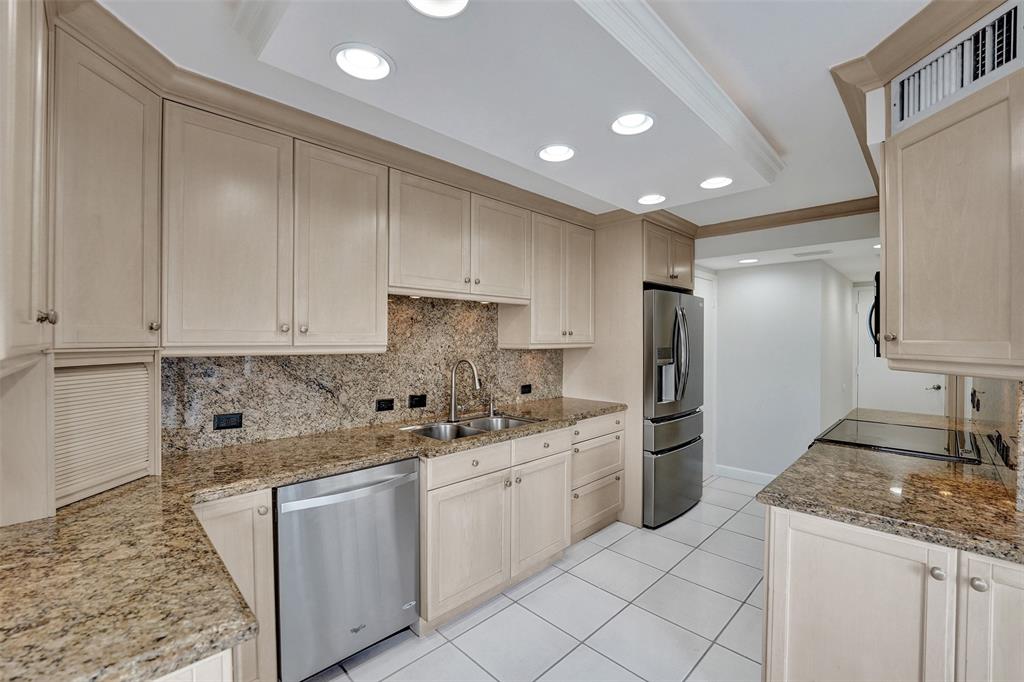936 Intracoastal Drive, Unit 12C Fort Lauderdale, FL 33304 - Photo 41 of 65 a kitchen with kitchen island granite countertop white cabinets sink and stainless steel appliances