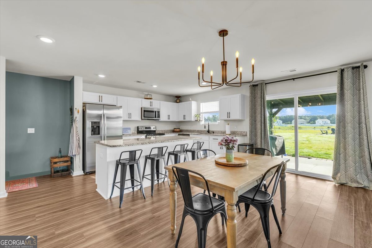 590 Wilkins Road Midway, GA 31320 - Photo 15 of 62 a dining room with stainless steel appliances a dining table wooden floor and a view of kitchen