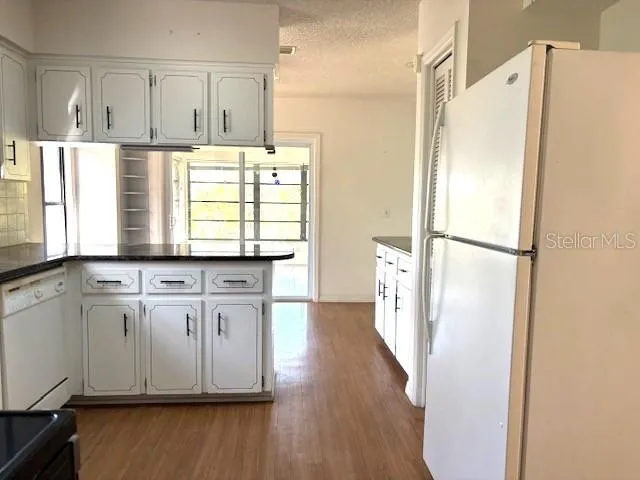 an empty room with wooden floor ceiling fan and windows
