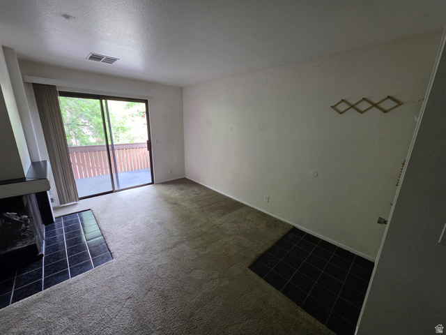 6852 Countrywoods Circle, Unit 5D Midvale, UT 84047 - Photo 7 of 50 Living area featuring wall-to-wall carpeting, a fireplace with a black tile hearth, and sliding glass doors leading to a private balcony with wooden railings