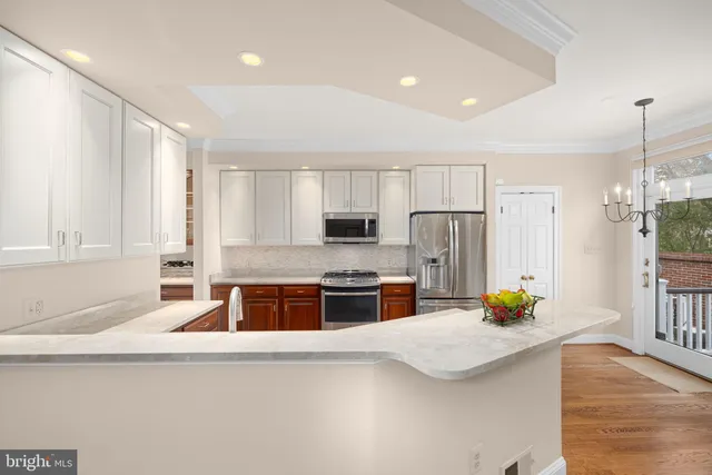 a kitchen with stainless steel appliances a stove a sink a refrigerator white cabinets and a refrigerator