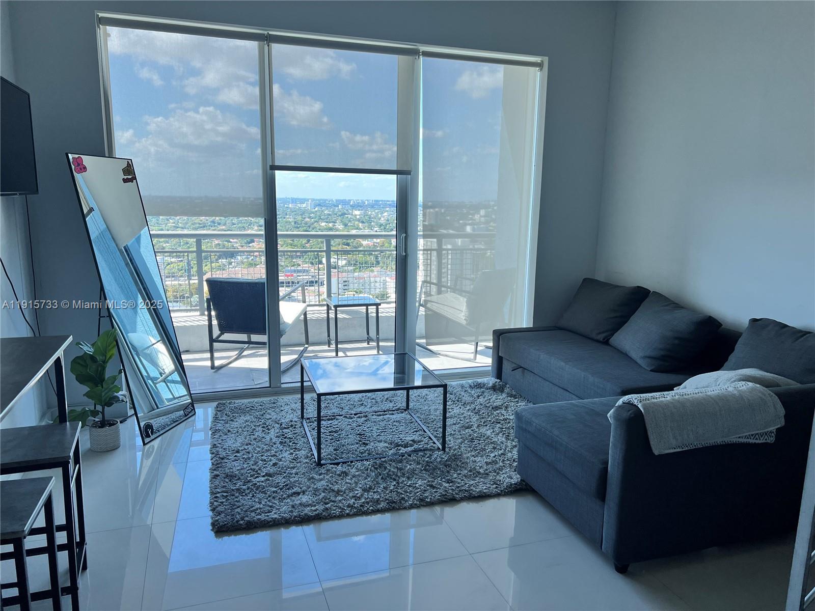 60 Southwest 13th Street, Unit 2207 Miami, FL 33130 - Photo 2 of 9 a living room with furniture and a floor to ceiling window