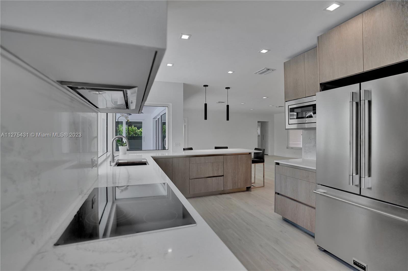 1311 Mulberry Way Boca Raton, FL 33486 - Photo 9 of 45 a kitchen with stainless steel appliances kitchen island granite countertop a refrigerator a sink dishwasher a stove and white countertops with wooden floor