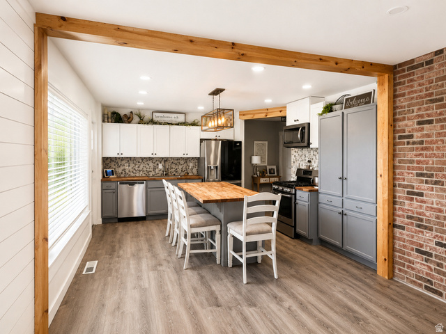 303 North Main Street Grace, ID 83241 - Photo 10 of 22 Kitchen featuring a wood-finish island with seating, a mosaic tile backsplash, and stainless steel appliances