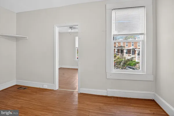 an empty room with wooden floor and windows