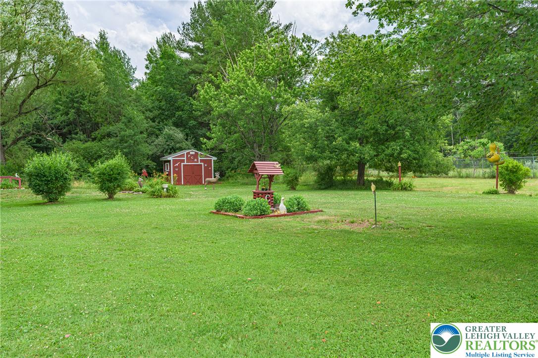 678 Interchange Road Kresgeville, PA 18333 - Photo 43 of 45 A verdant backyard with a charming shed and decorative wishing well, offering ample space for outdoor enjoyment.