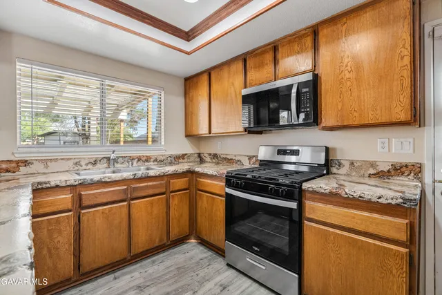 a kitchen with stainless steel appliances granite countertop wooden cabinets stove and a sink