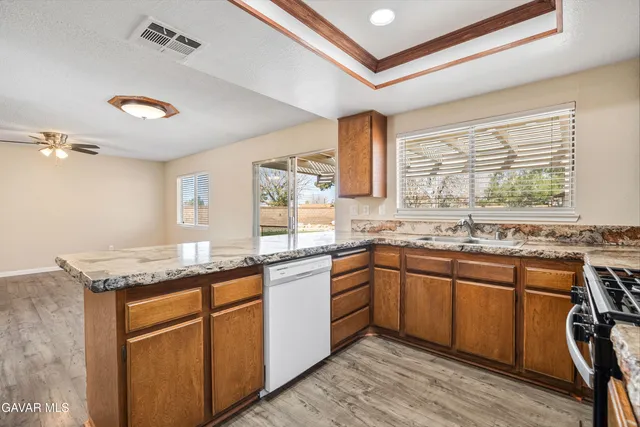 a kitchen with granite countertop stainless steel appliances sink stove and cabinets