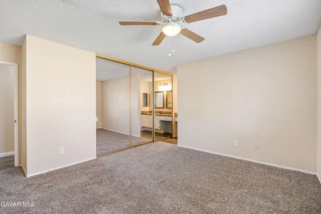 an empty room with chandelier fan and windows