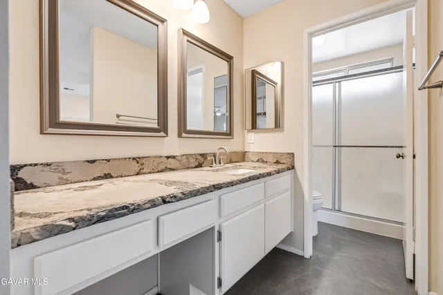 a bathroom with a granite countertop sink and a mirror