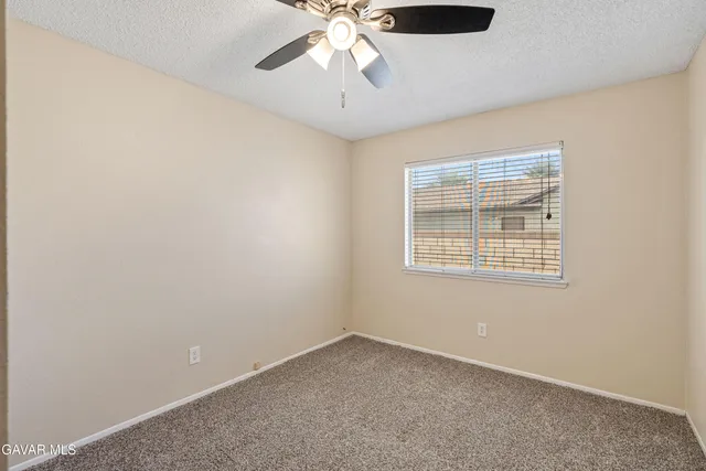 an empty room with a chandelier fan and windows