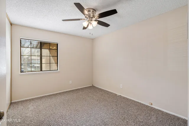 an empty room with a window and a ceiling fan