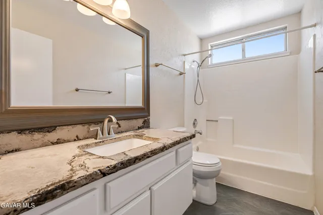 a bathroom with a granite countertop sink a toilet and shower