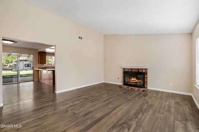 a view of an empty room with wooden floor and a fire place