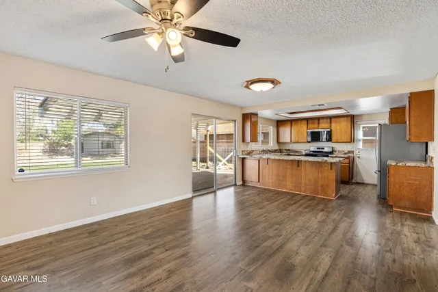 a large kitchen with stainless steel appliances granite countertop a stove a sink dishwasher and a refrigerator with wooden floor