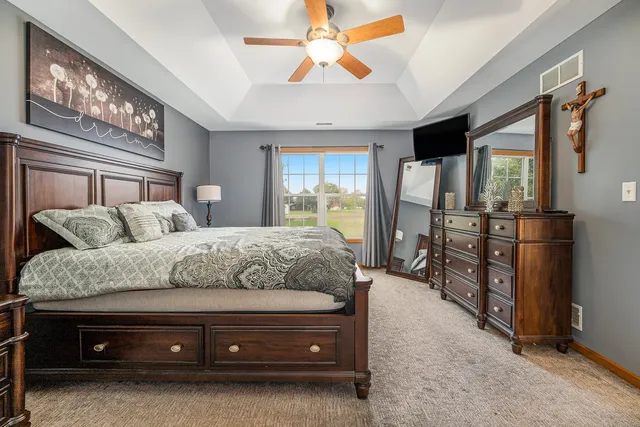a spacious bedroom with a bed a dresser and a chandelier