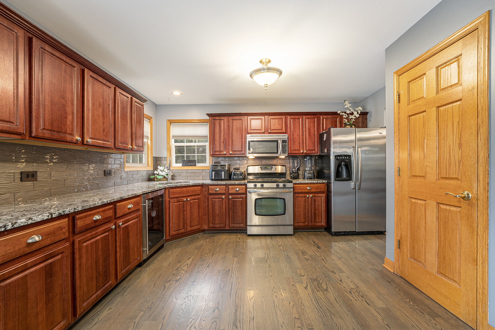 257 Pine Street Beecher, IL 60401 - Photo 6 of 31 a kitchen with stainless steel appliances granite countertop a refrigerator a sink dishwasher a stove and wooden cabinets with wooden floor