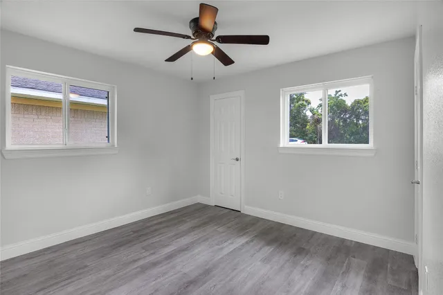 a view of empty room with wooden floor and fan
