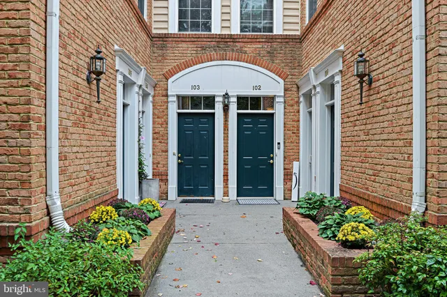 front view of a brick house with potted plants
