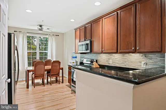 a kitchen with stainless steel appliances granite countertop a stove top oven a sink dishwasher and wooden cabinets with wooden floor